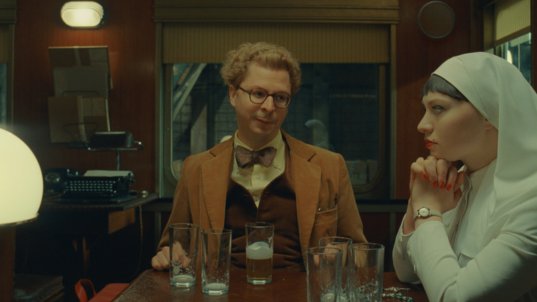 Bjørn and Liesl make eye contact at a table with glasses of beer in 