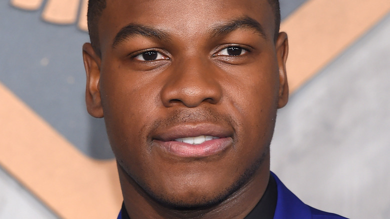 John Boyega grinning slightly for a press photo