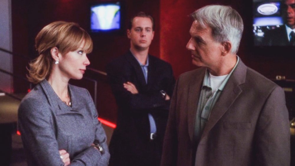 Lauren Holly as Jenny Shepard folds her arms and stares down Mark Harmon as Agent Gibbs while Sean Murray as Tim McGee watches in the background in NCIS