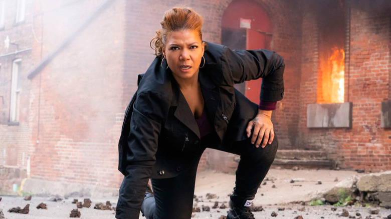 Robyn posing on ground with burning building in background