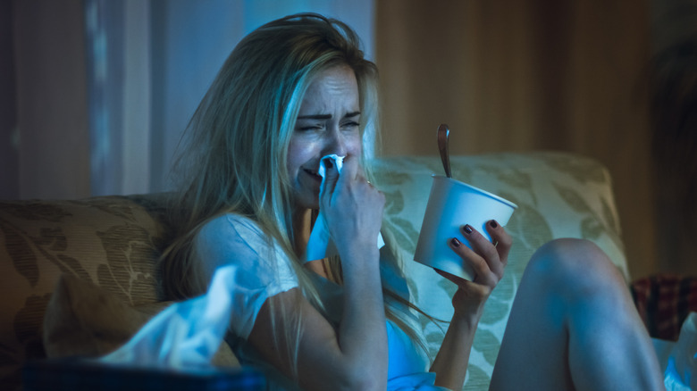 Woman crying while watching TV and eating