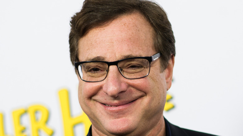 Bob Saget smiles and wears glasses