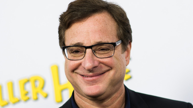 Bob Saget smiles and wears glasses