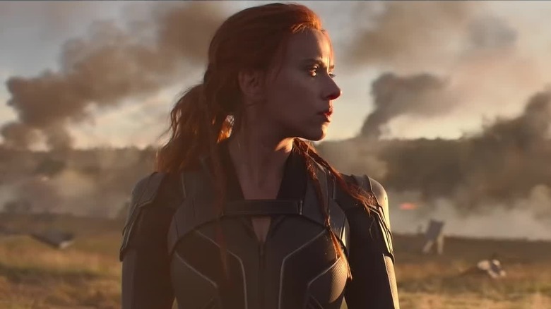 Natasha stands in front of smoky rubble in "Black Widow" (2021)
