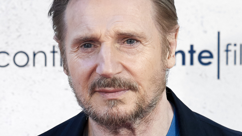 Liam Neeson smiling with stubble