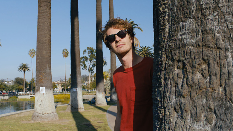 Sam looking out from behind a tree in Under the Silver Lake (2018)