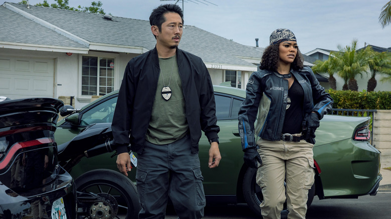 Detective Mike Ro and Detective Numa Baptiste standing outside by cars