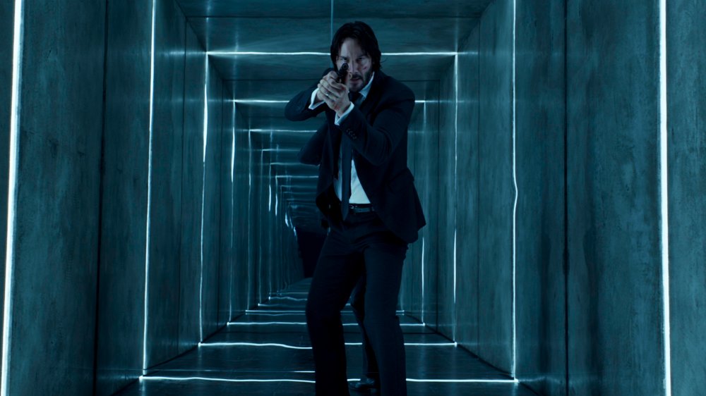 John Wick, pistol drawn, enters the Reflections of the Soul exhibit