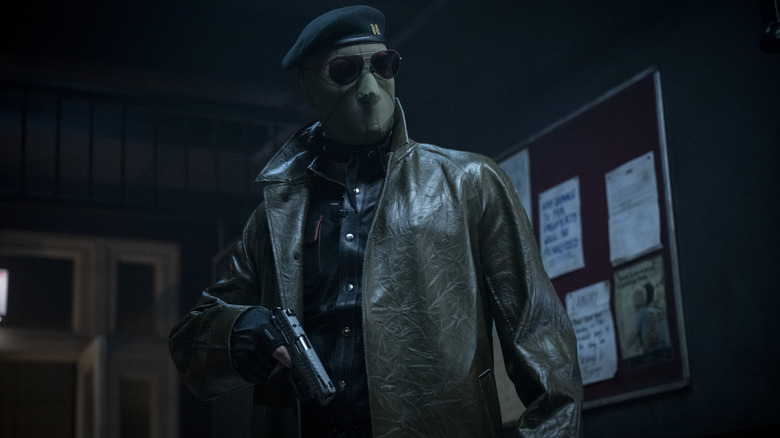 McCone standing in a dark hall (2025)