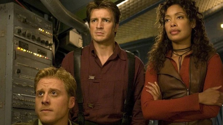 Wash, Mal, and Zoe standing in the Serenity's cockpit in Firefly (2002)