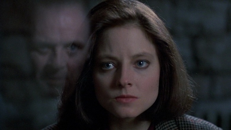 Clarice Starling's face is seen through glass that reflects Hannibal Lecter's face