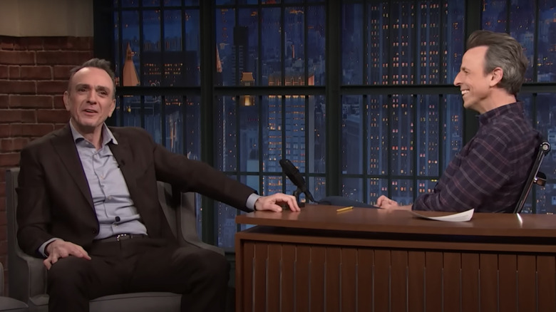 Hank Azaria smiling while speaking with Seth Meyers