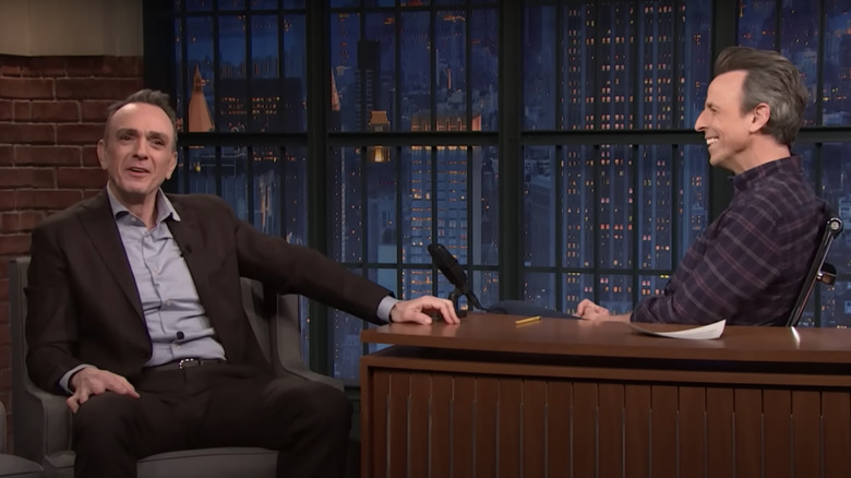 Hank Azaria smiling while speaking with Seth Meyers