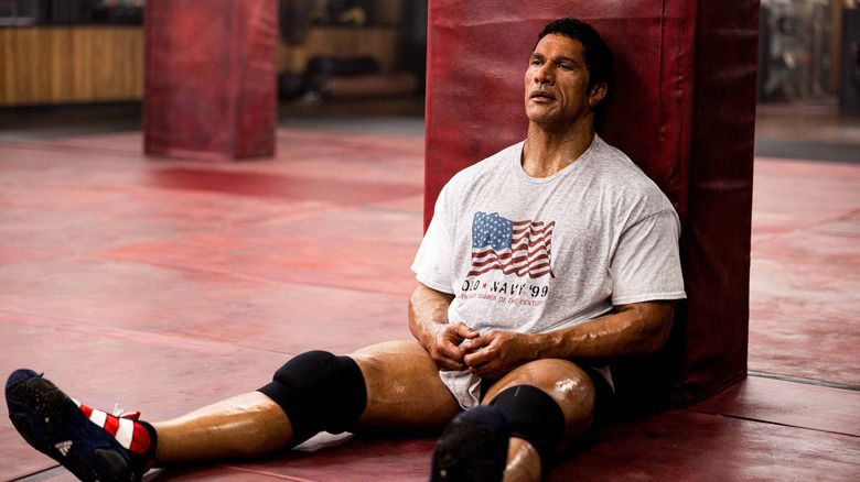 Mark Kerr sits on a gym mat in "The Smashing Machine" (2025)