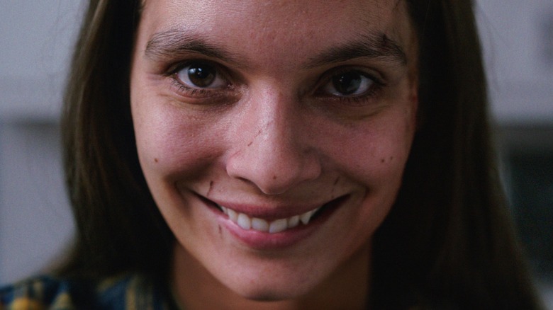 Laura wearing a creepy smile in 