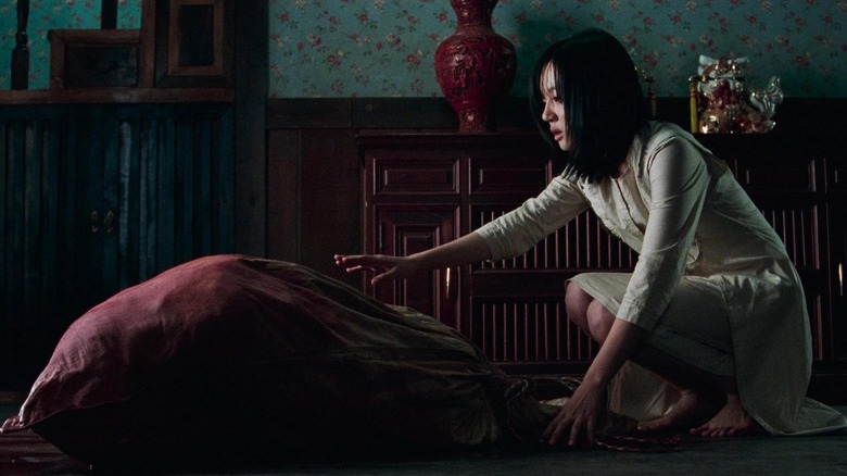 A woman reaches out to a sinister bag in A Tale of Two Sisters