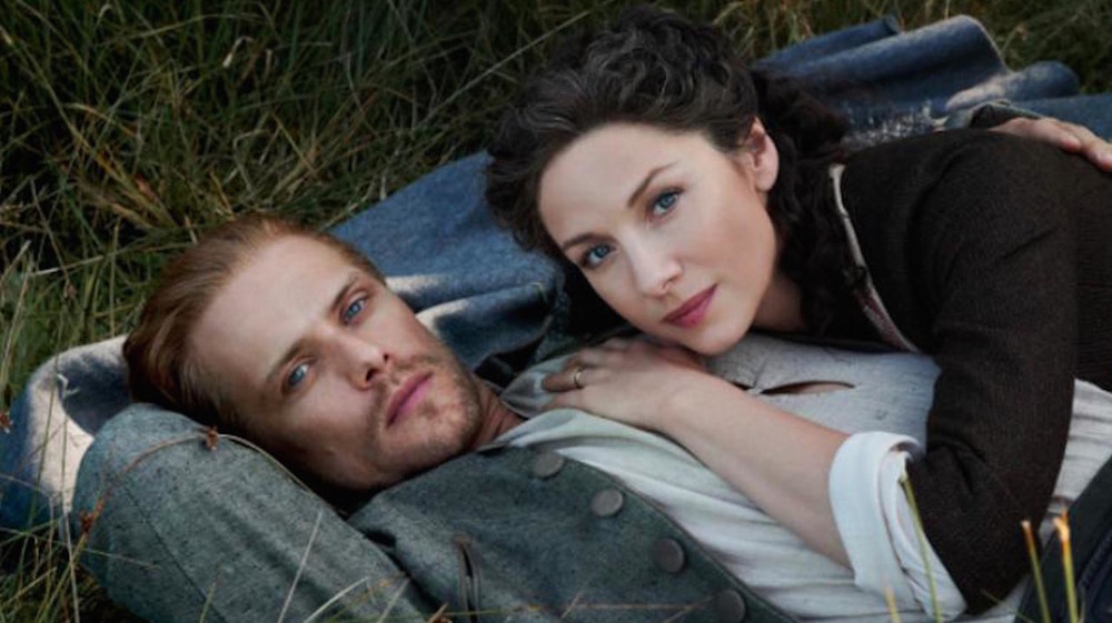 Caitríona Balfe and Sam Heughan lying on the grass