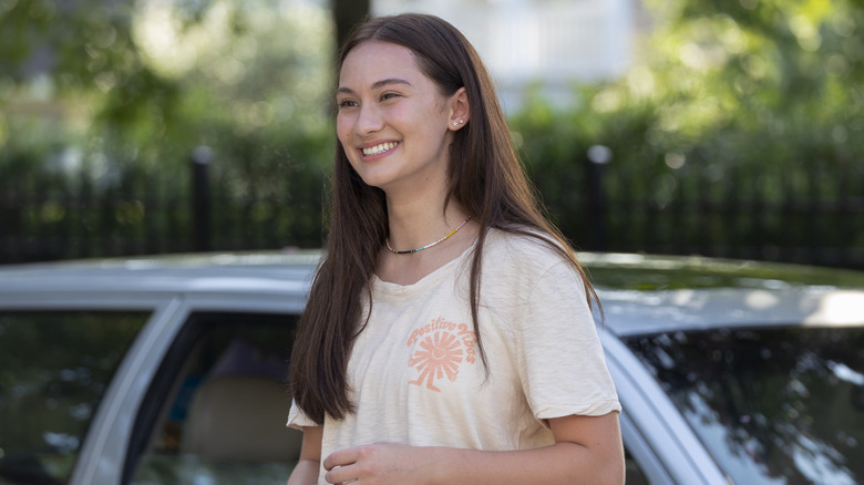 Belly smiling in front of a car in "The Summer I Turned Pretty" Season 1.