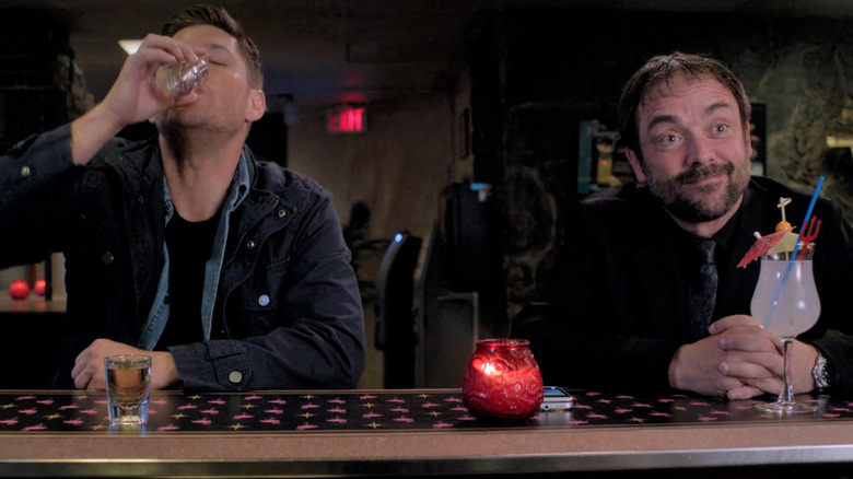 Dean Winchester and Crowley drinking at bar
