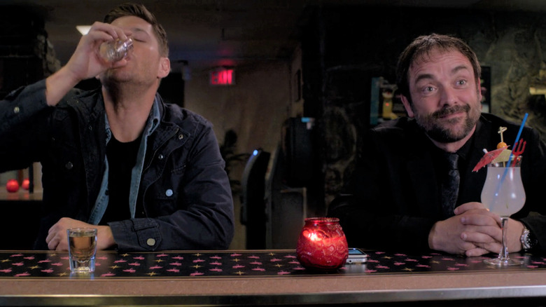 Dean Winchester and Crowley drinking at bar