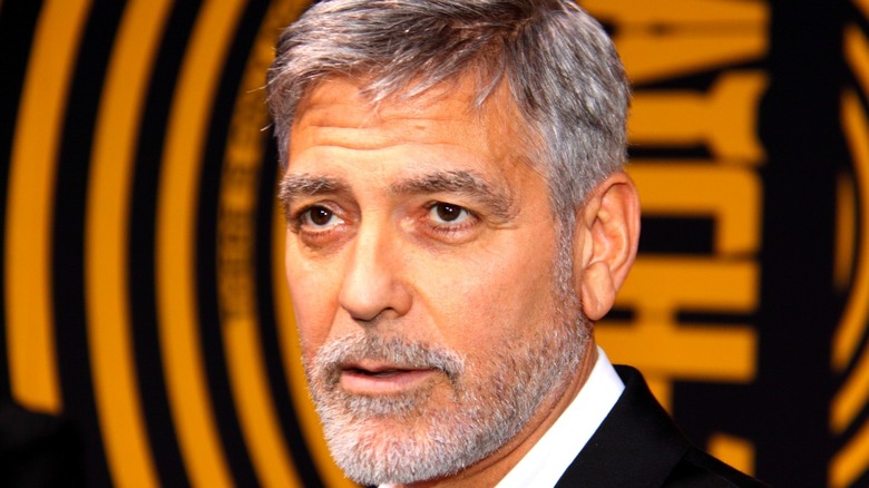 George Clooney in front of a black-and-orange background