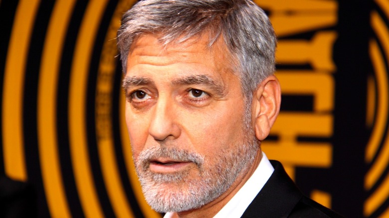 George Clooney in front of a black-and-orange background