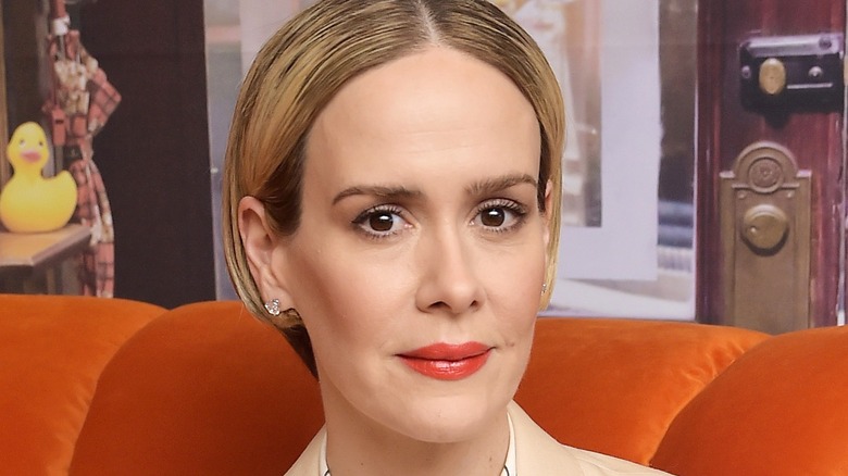 ECU of Sarah Paulson with orange lipstick on orange couch