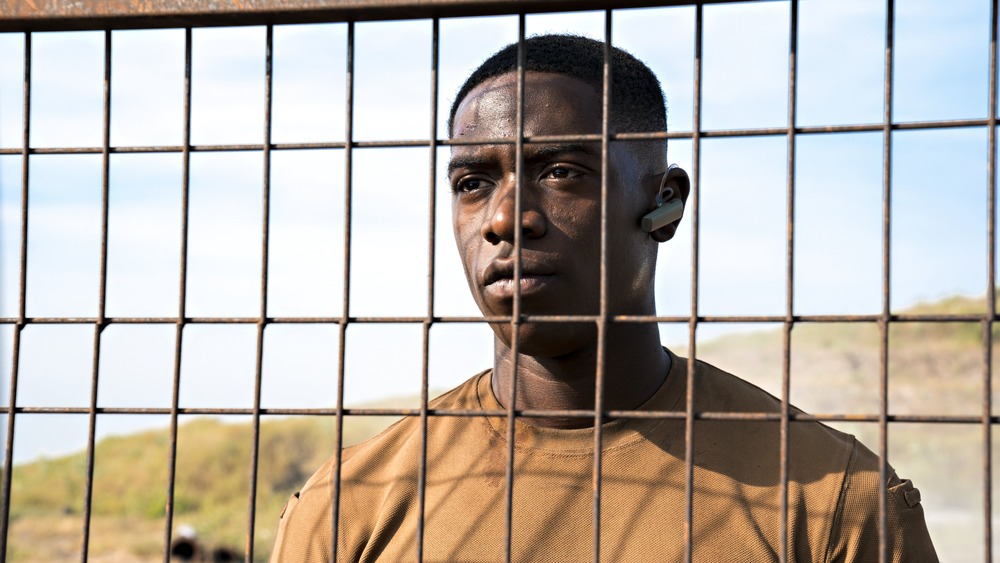 Damson Idris as Harp peers through a fence