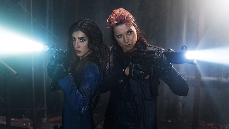 Dana DeLorenzo and Lucy Lawless holding rifles