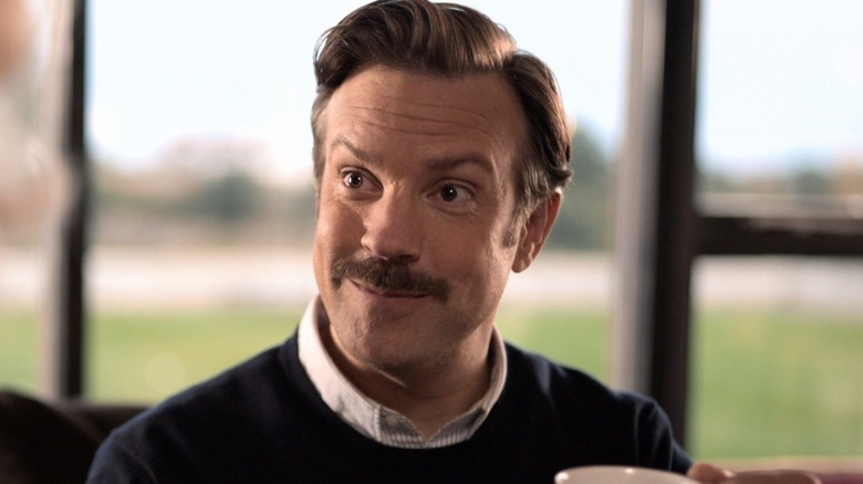 Ted Lasso smiles while drinking tea