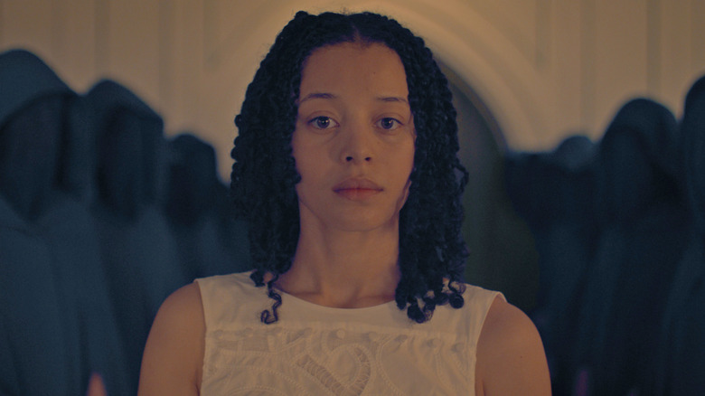 Agnes stands among hooded figures in 