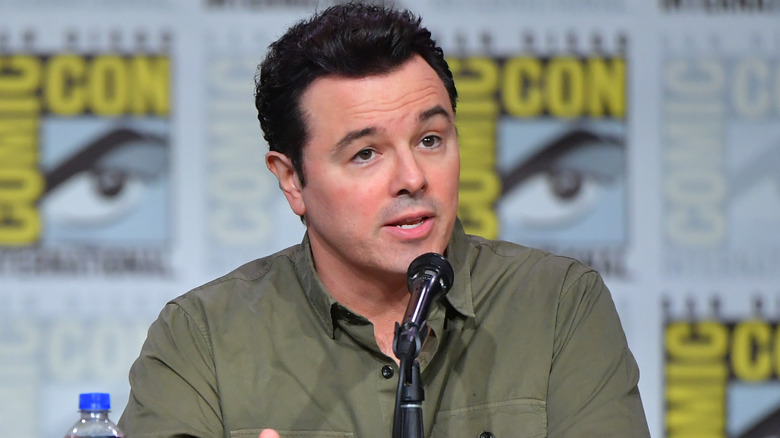 Seth MacFarlane in front of a microphone in a green shirt