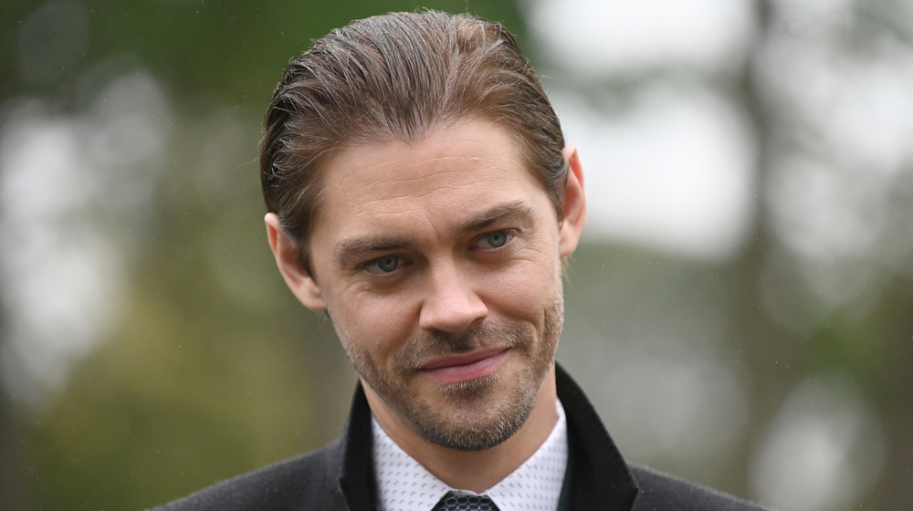 Tom Payne with slicked-back hair