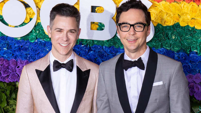 Todd Spiewak and Jim Parsons smiling in front of rainbow flowers