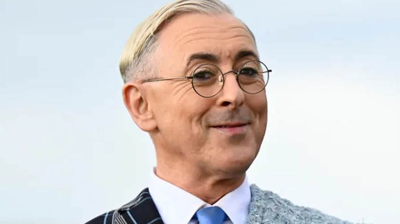 Alan Cumming on the Traitors with his arms outstretched