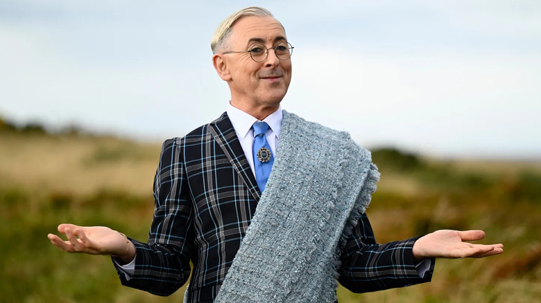 Alan Cumming on the Traitors with his arms outstretched