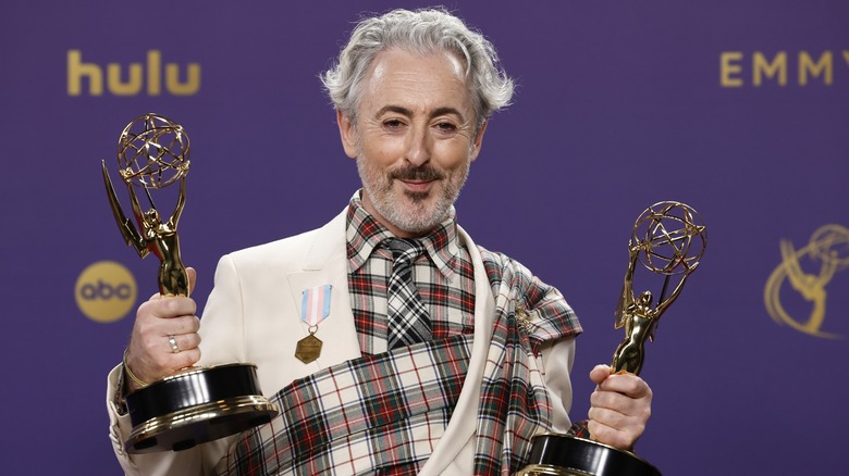 Alan Cumming holding his Emmy Awards