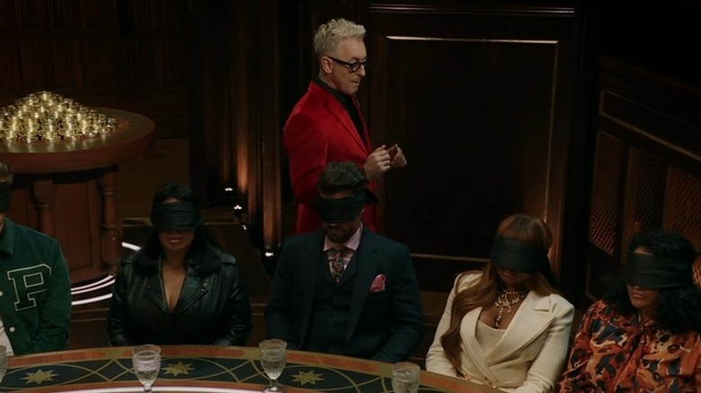 Alan Cumming stands behind the blindfolded contestants on "The Traitors" (2023-present)