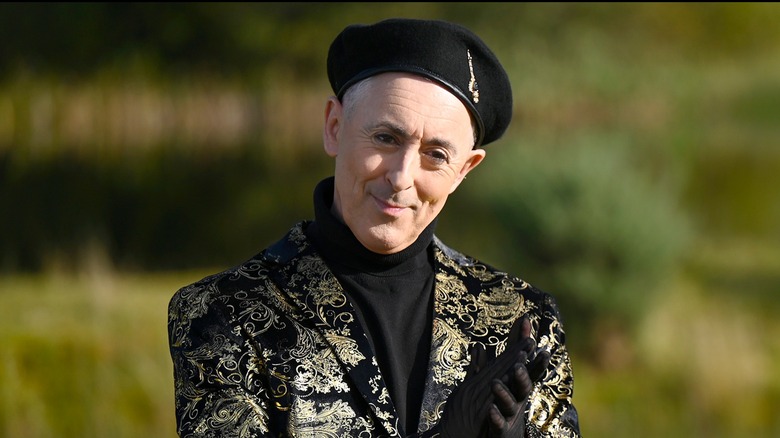 Alan Cumming in gold filigree jacket and beret on "The Traitors"