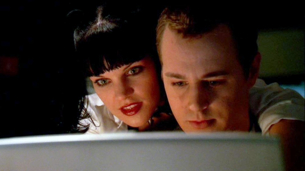 Pauley Perrette as Abby Sciuto leans over Sean Murray as Tim McGee while he uses a computer in NCIS