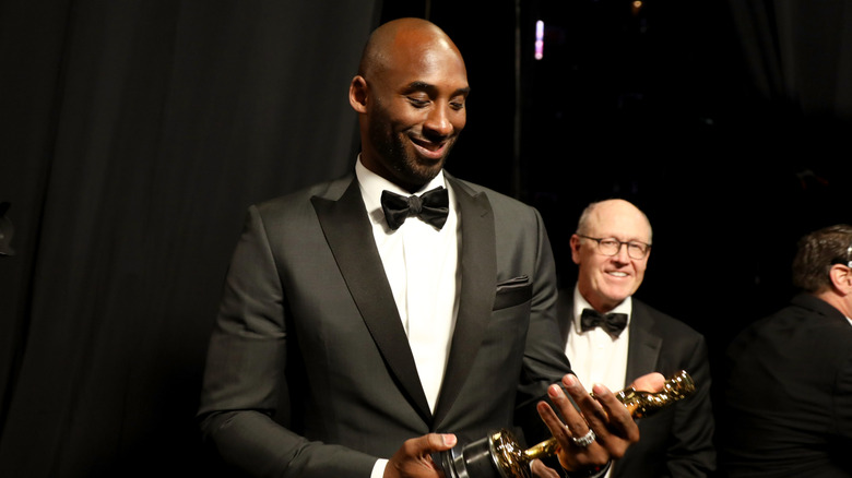 Kobe holding his Oscar and smiling