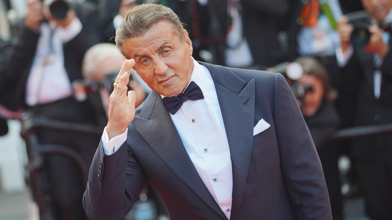 Sylvester Stallone wearing suit saluting