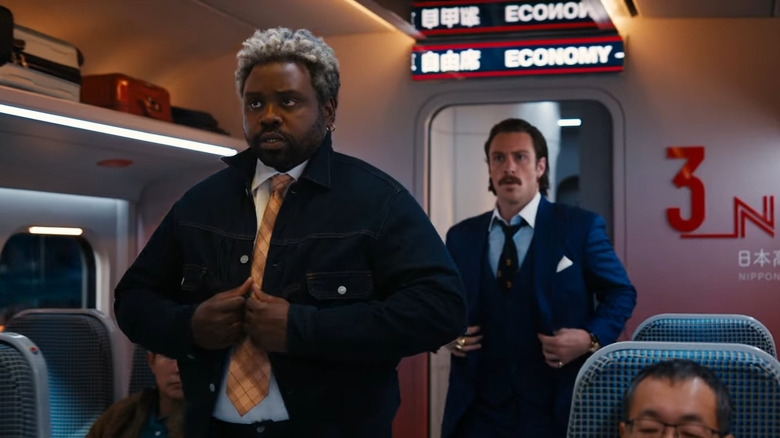 Brian Tyree Henry and Aaron Taylor-Johnson standing in train compartment