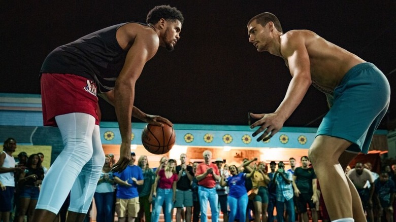 2 men playing basketball with a crowd