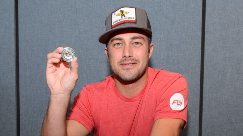 Taylor Kinney in a hat on a spin bike