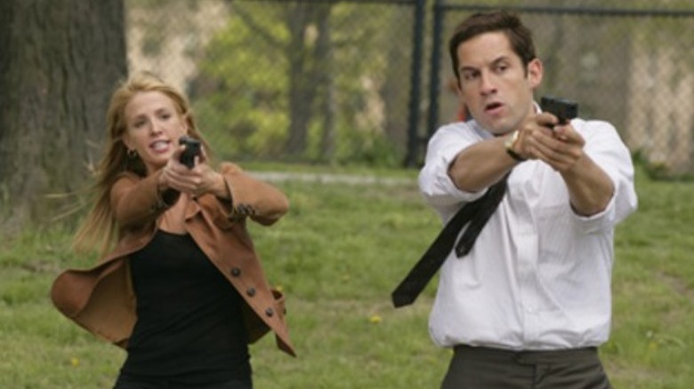 Enrique Murciano and Poppy Montgomery aiming guns