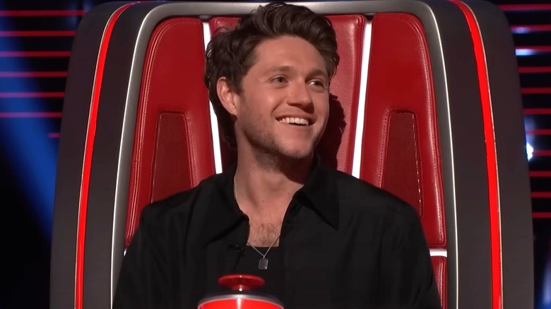 Niall Horan smiling sitting red chair