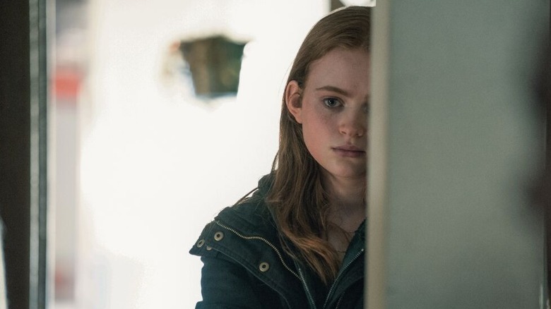Ellie stands behind the door
