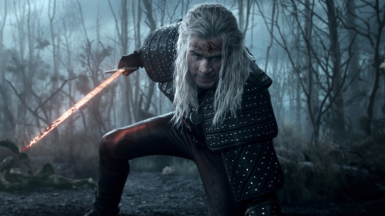 Liam Hemsworth's Geralt of Rivia holding his flaming sword in The Witcher