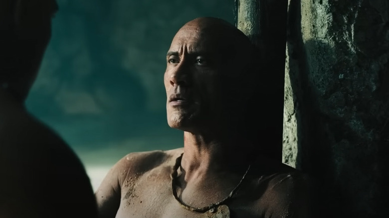 Black Adam leans against a pillar